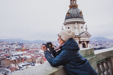 Tourist woman takes pictures from St. Stephens Basilica, Budapest, Hungary on a snowy day.