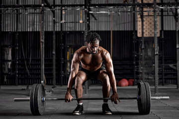 Young muscular african sweaty fit man with big muscles training with heavy barbell weight during cross training workout in modern gym. handsome guy is engaged in sport, fitness, pumping arm muscles - obrazy, fototapety, plakaty