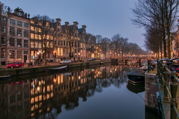 Illuminated reflections in the Herengracht canal in Amsterdam at dusk
