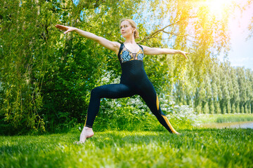 Fototapeta na wymiar young woman doing yoga asana in park. girl stretching exercise in yoga position. happy and healthy woman sitting in lotus position and practicing yoga. meditation and sport on sunset outdoors 
