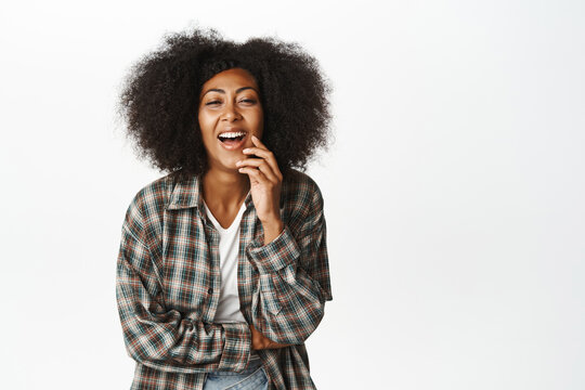Image of carefree black woman laughing and smiling, looking joyful, standing in casual relaxed pose, having fun, standing over white background