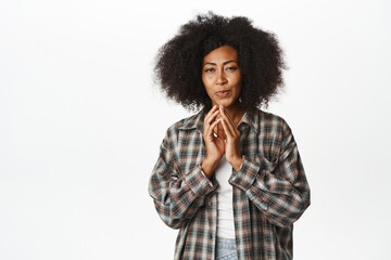 Fototapeta na wymiar Cunning african american woman has plan, scheming, steeple fingers and smirking devious, has an idea, thinking smth interesting, standing over white background