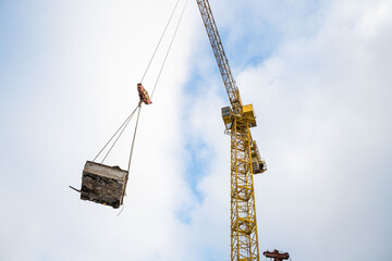 a construction crane unloads a trough in a blue sky with clouds,