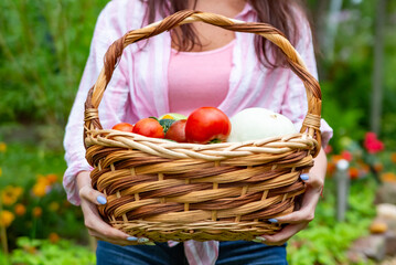 faceless happy smiling woman farmer hold a basket of vegetables from her garden.