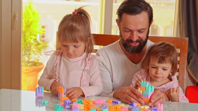 Happy Father plays constructor game with daughters