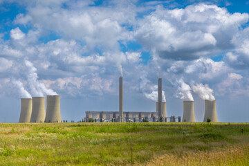 Coal fired power station in South Africa with smoke and steam rising from the smoke stacks and cooling towers - obrazy, fototapety, plakaty