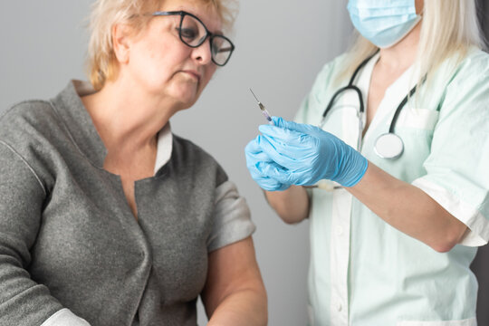 Senior vaccination concept. Elderly getting immune vaccine at arm for flu shot, pneumonia, and shingles in hospital by nurse. Doctor giving an injection to older people patient in clinic