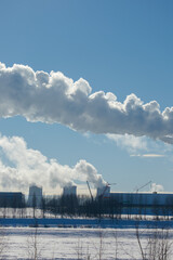 Winter landscape, snow-covered field and in the distance there are CHP chimneys on the horizon and...
