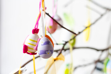 Tree branches decorated with Easter eggs and feathers in a glass vase.