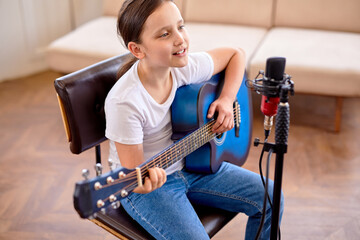 Play on. Cute child girl vocal artist singing in modern recording studio in order to create new...