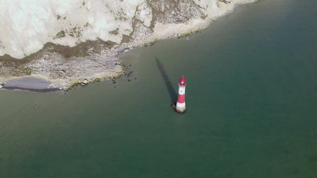Aerial shot of Beachy Head lighthouse at abase of tall white cliff, UK