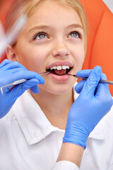 beautiful european child girl visiting dentist, doctor doing dental examination before treatment, ideal teeth. close-up photo of face. healthcare, wellbeing, medicine, lifestyle concept