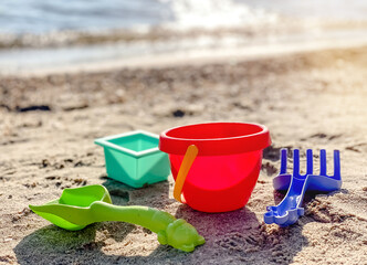 Toys shovel, rake and bucket for childrens sandbox on the beach. Childrens toys
