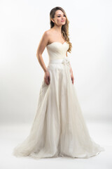 Fototapeta premium Beautiful attractive bride in wedding dress with long full skirt, white background