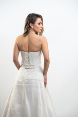 Fototapeta premium Beautiful bride with fashion hairstyle and make-up wearing wedding dress on white background 