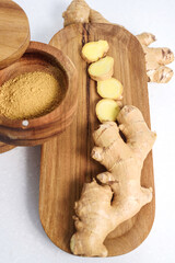 Fototapeta na wymiar Ginger root and ginger powder in the wooden bowl, vertical photo
