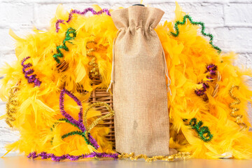Mardi Gras Mockup. Empty blank wine gift bag with yellow feather boa on table. Mardi Gras party...