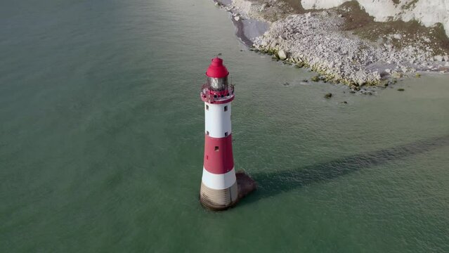 Aerial shot of Beachy Head lighthouse at abase of tall white cliff, UK