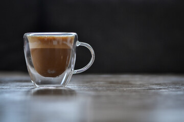 A cup of espresso was placed on a wooden table on a black background
