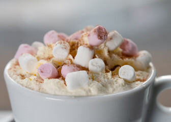 cup of coffee or hot chocolate with marshmallow on the table in cafe against window in snowing winter day