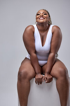 Fotka „Excited fat black woman in white bodysuit on white background  isolated. Free space for text mockup. Perfect chubby sexy body with smooth  soft skin. Wellness, hair removal, body care, body positive“ ze