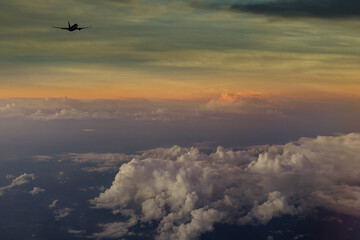 Evening sky with dramatic clouds over airplane in the sky at sunrise