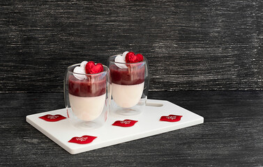two desserts in a glass glass with hearts on a black wooden background