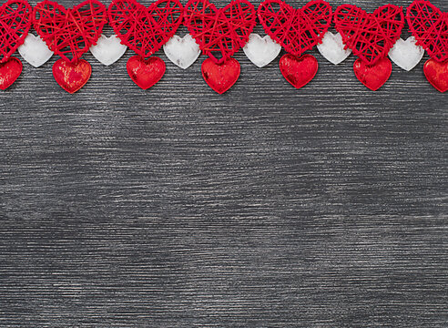 ornament of red and white hearts on a black wooden background. Valentine's day concept