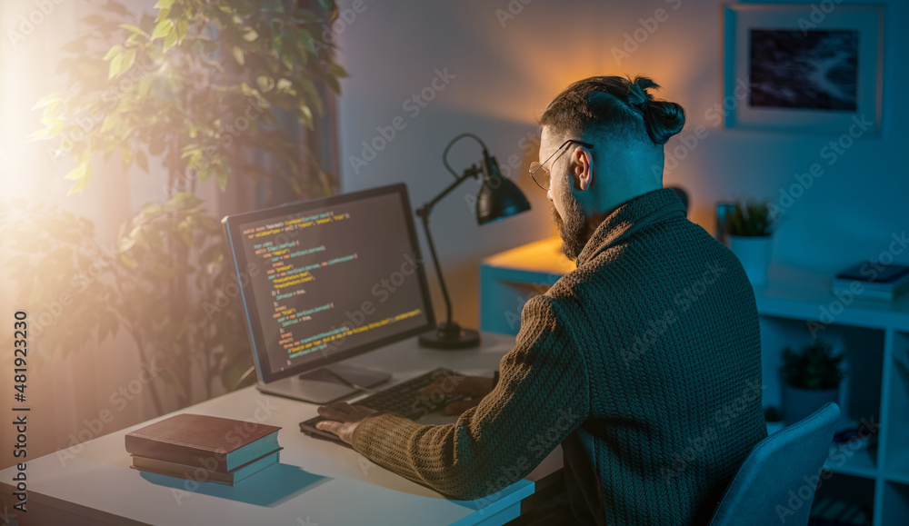 Poster professional it specialist sitting at home during evening time and writing data code on modern pc. c
