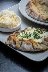 Traditional Finnish foods - Fresh Karelian pies with rice pudding filling and egg butter and chives topping against black background. - obrazy, fototapety, plakaty