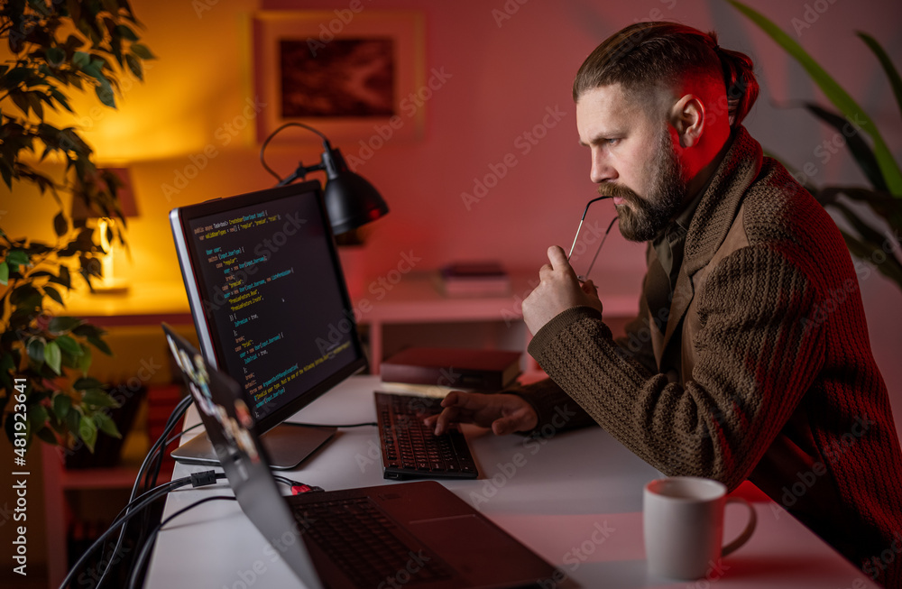 Aufkleber thoughtful bearded man sitting at desk and looking on monitor with data code. male developer working