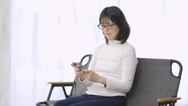 スマートフォンでテキスト入力をするアジア人の女性