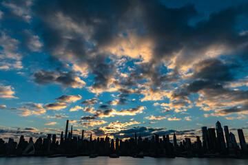 Fototapeta na wymiar Vivid sunrise over Manhattan skyline with illuminated clouds above the buildings.