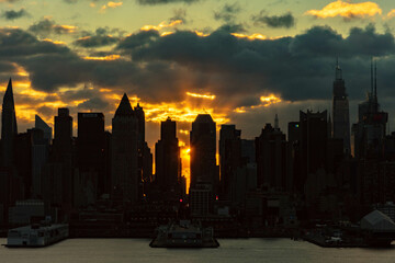 Vivid sunrise over Manhattan skyline with illuminated clouds above the buildings.
