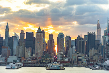 Fototapeta premium Vivid sunrise over Manhattan skyline with illuminated clouds above the buildings.