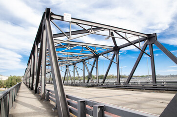 Fototapeta na wymiar Steel bridge structure with Cycleway alongside it on beautiful cloudy, blue sky day.