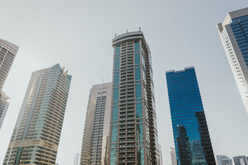 Fototapeta premium Modern city skyscrapers buildings at sunset time with business and residential towers around the lake and palm trees