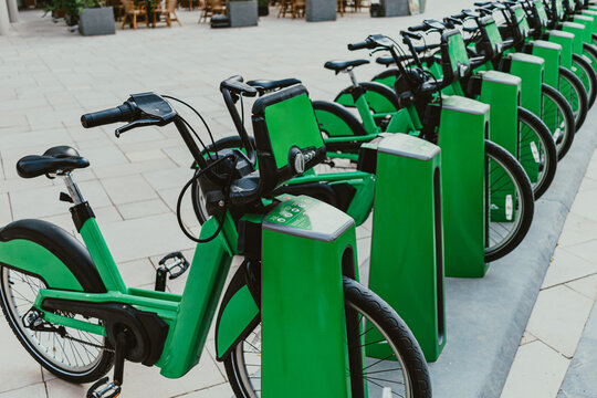 Green eco-friendly bike public rentals in a row located outside in a park area