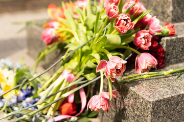 Several flowers near the monument. Marble or granite slab of the monument. stone background. Day of Victory and Sorrow. Memorial Day of the war. Victims.