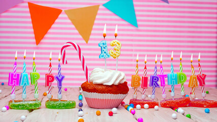 Happy birthday card to a thirteen year old child on a pink background, with a number in a cupcake....