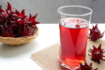 Ice roselle juice  in glass with fresh roselle fruit on the table. healthy herbal drink concept.