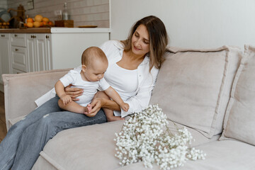 mom and baby on the bed with a bouquet of white flowers