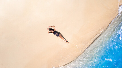 Aerial view, women lounging, sunbathing on the beach and beautiful blue water waves on the island of Thailand.