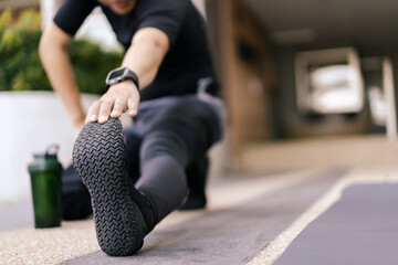 Happy Asian young sportsman doing a lower and upper body stretching before making an exercise in a park.