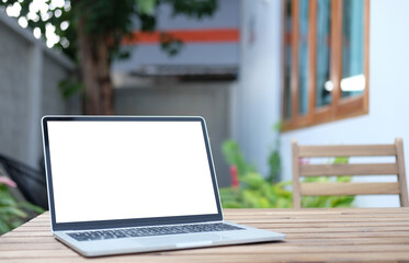 Computer laptop with white empty screen on wooden table at outdoor cafe.