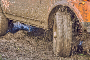 Fototapeta na wymiar Orange 4x4 off-road car rides skidding through the mud, the ground flies from under the wheels. Extreme off-road competition on an off-road vehicle. The concept of adventure travel.
