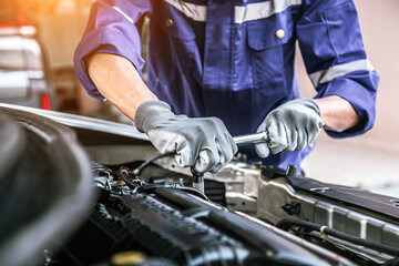 Car care maintenance and servicing, Close-up hand technician auto mechanic using the wrench to...