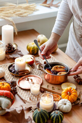 Young woman preparing delicious sweet homemade autumn hot drink: mulled wine with spices. Cozy home atmosphere, wooden background