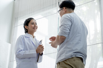 Obraz premium Doctor smile and the patient discuss together in front of glass window with curtain in the room at day time.