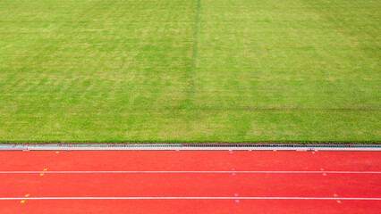 Athletics Track Lane or running track and green grass at football or soccer stadium.